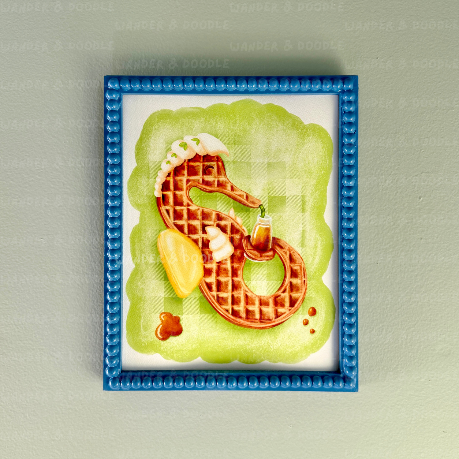 Framed artwork of a waffle in the shape of a seahorse on a green background